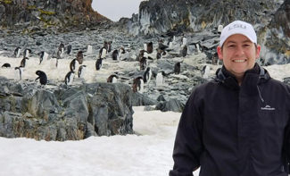 Researcher Mike Polito standing in front of a group of penguins in Antarctica