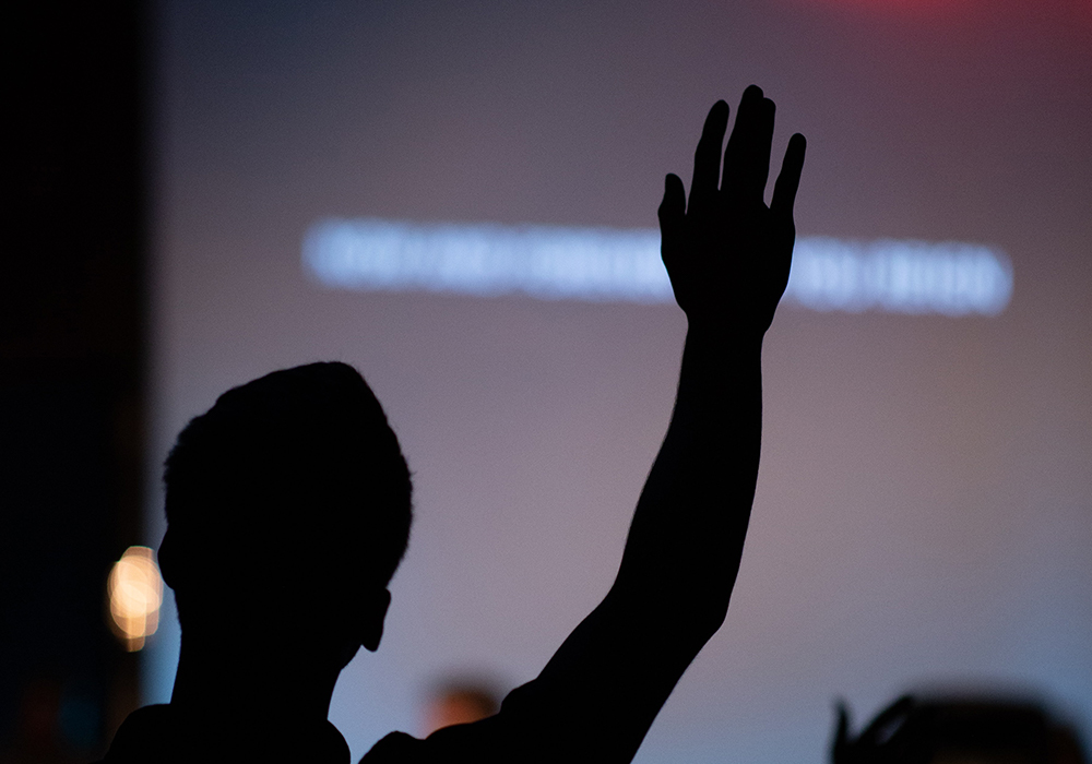 Person raising their hand in a dark room during a presentation