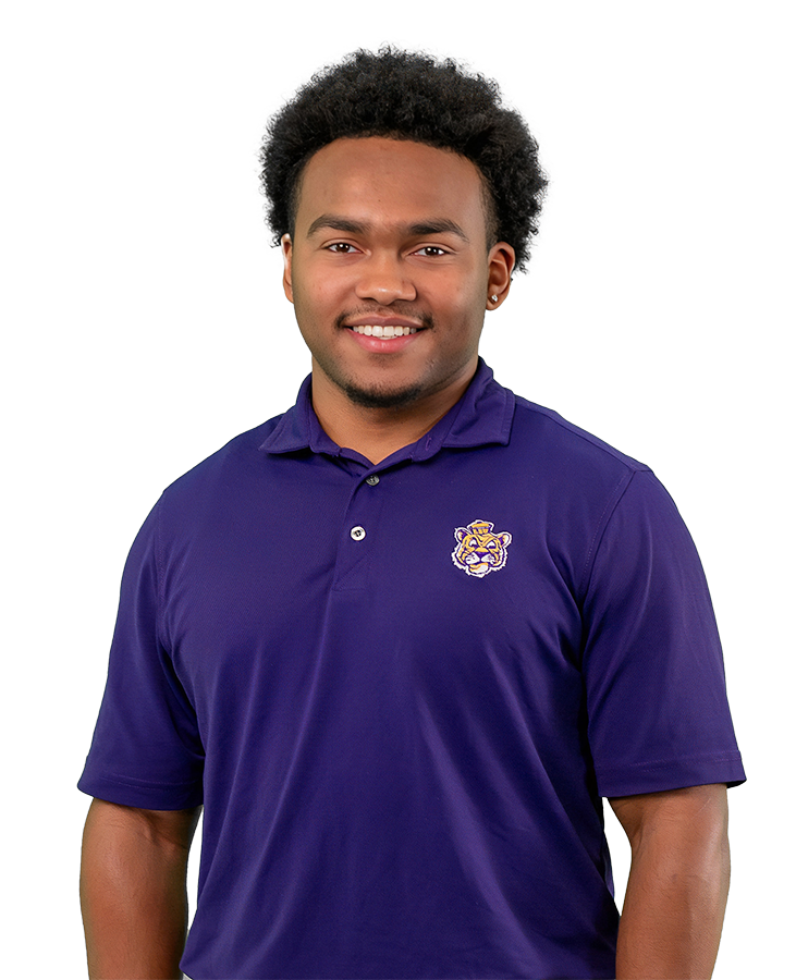 Mekhi wears a purple polo with a retro Mike logo embroidered on it. 