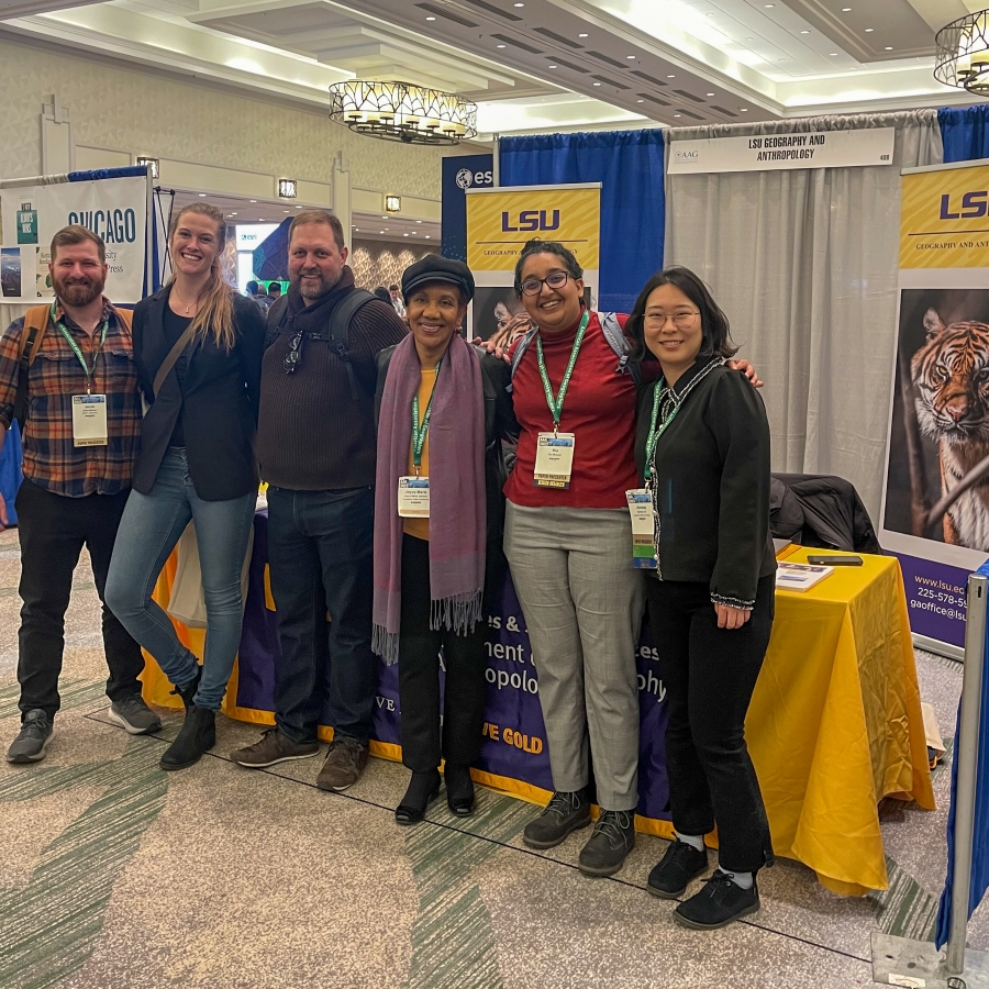 a team of researchers stand in front of a table decorated with LSU merch