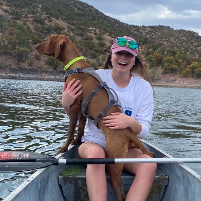 Reilly in a canoe on the water with a dog in her lap. 